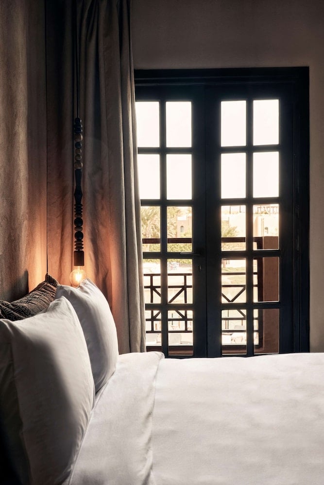 Cook's Club El Gouna (Adults Only) bedroom with a white bed and black-framed glass doors.