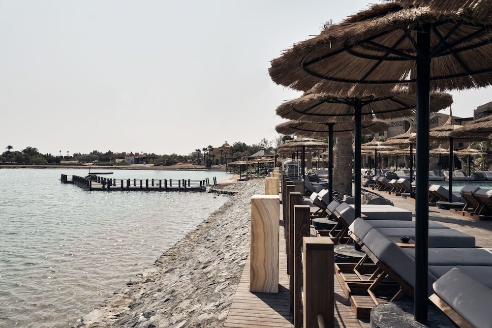 Cook's Club El Gouna (Adults Only) waterfront deck with thatched parasols and sun loungers.