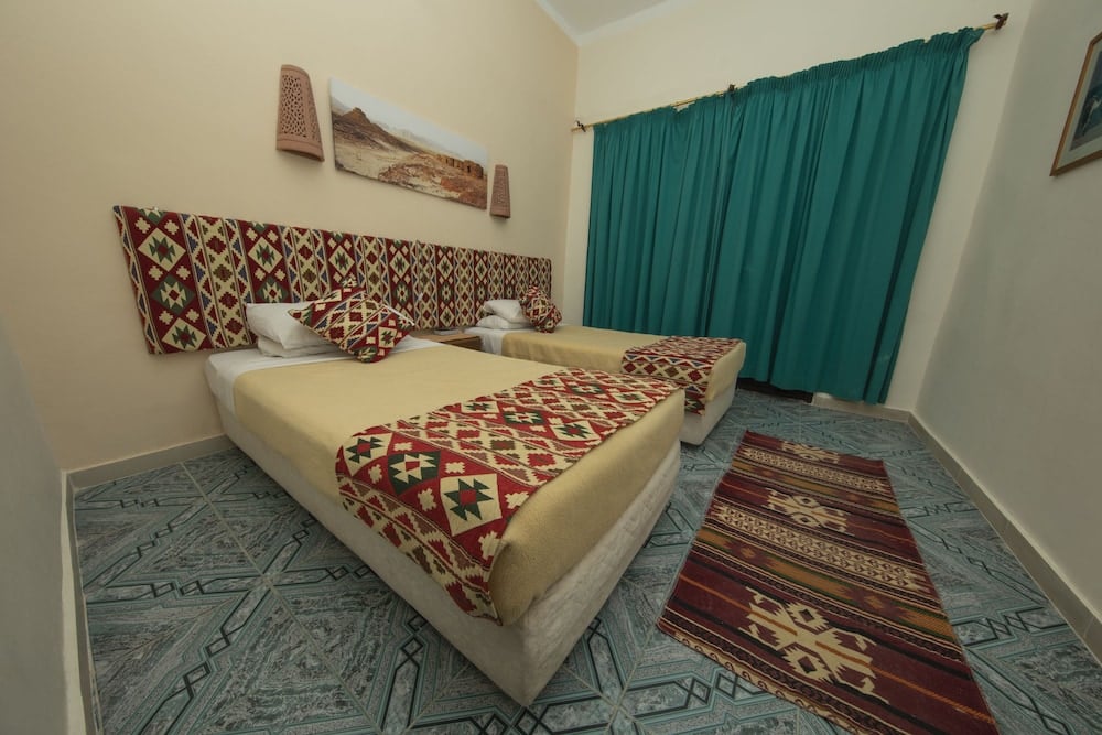 The Bedouin Moon Hotel Dahab twin bedroom with two single beds and teal curtains.