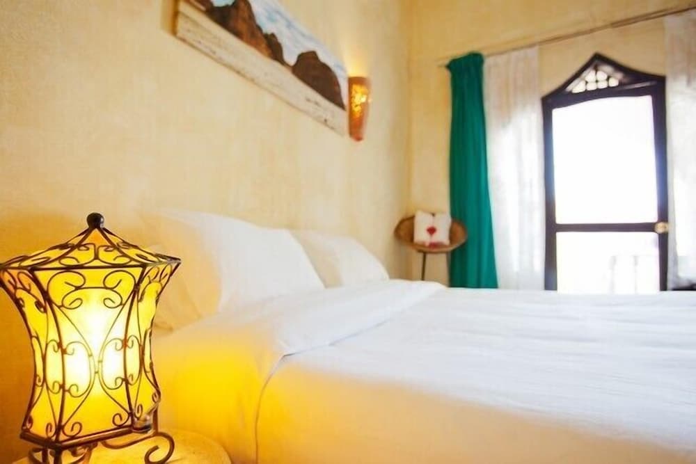The Bedouin Moon Hotel Dahab guest room with a white bed and an arched window.