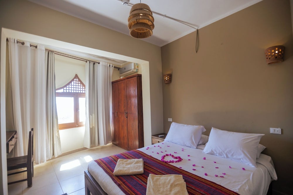 The Bedouin Moon Hotel Dahab bedroom with a double bed and wooden wardrobe.