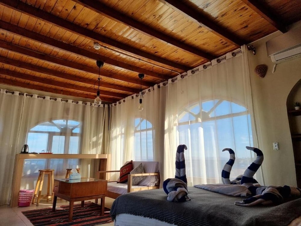 The Bedouin Moon Hotel Dahab bedroom with a large bed and arched windows.