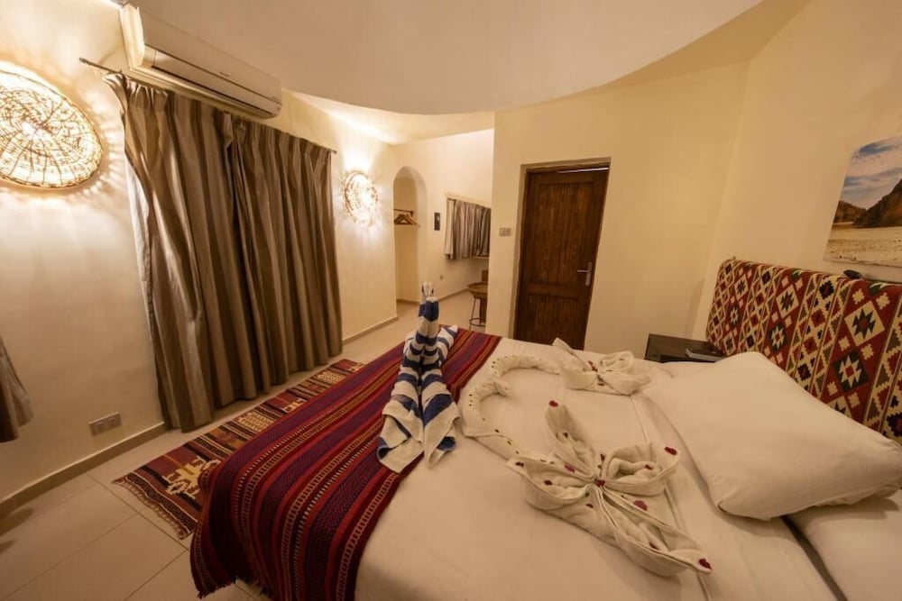 The Bedouin Moon Hotel Dahab bedroom with a white bed and striped rug.