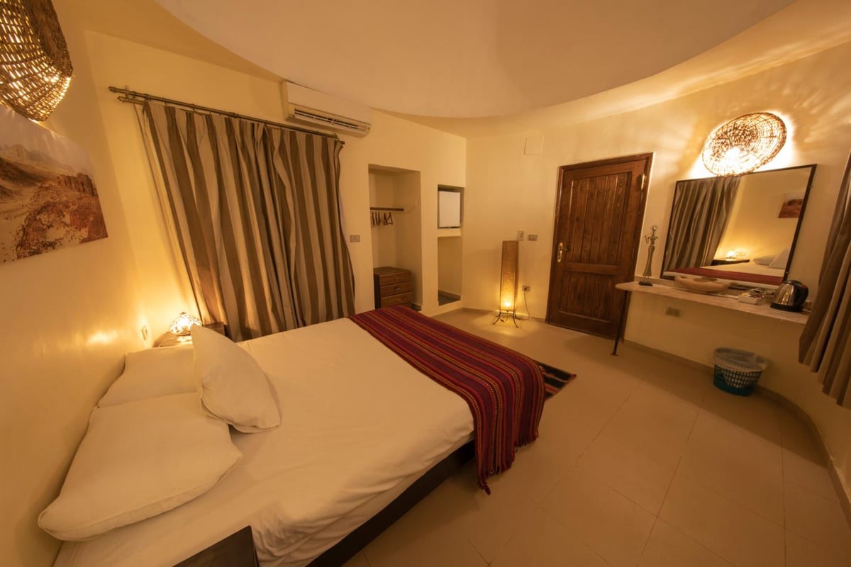 The Bedouin Moon Hotel Dahab guest room with a white bed and striped curtains.