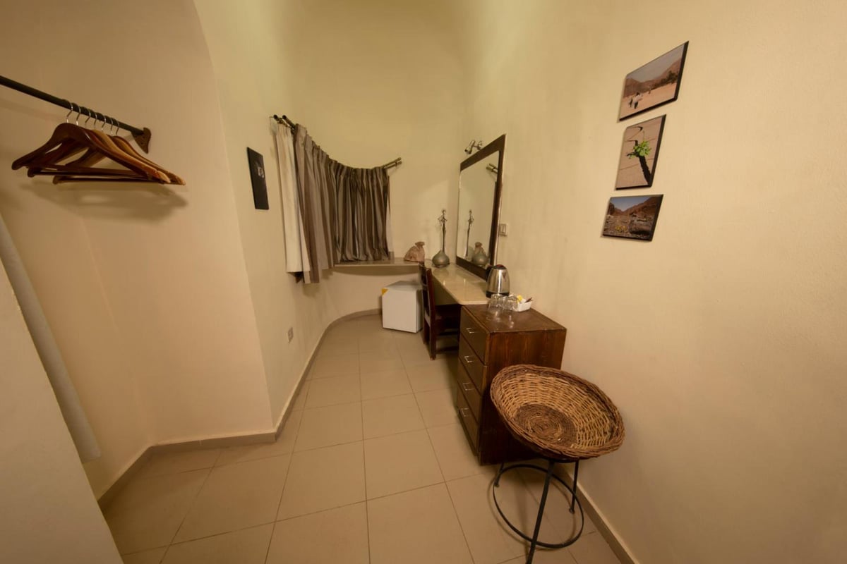 The Bedouin Moon Hotel Dahab dressing area with a wooden dresser and clothing rack.