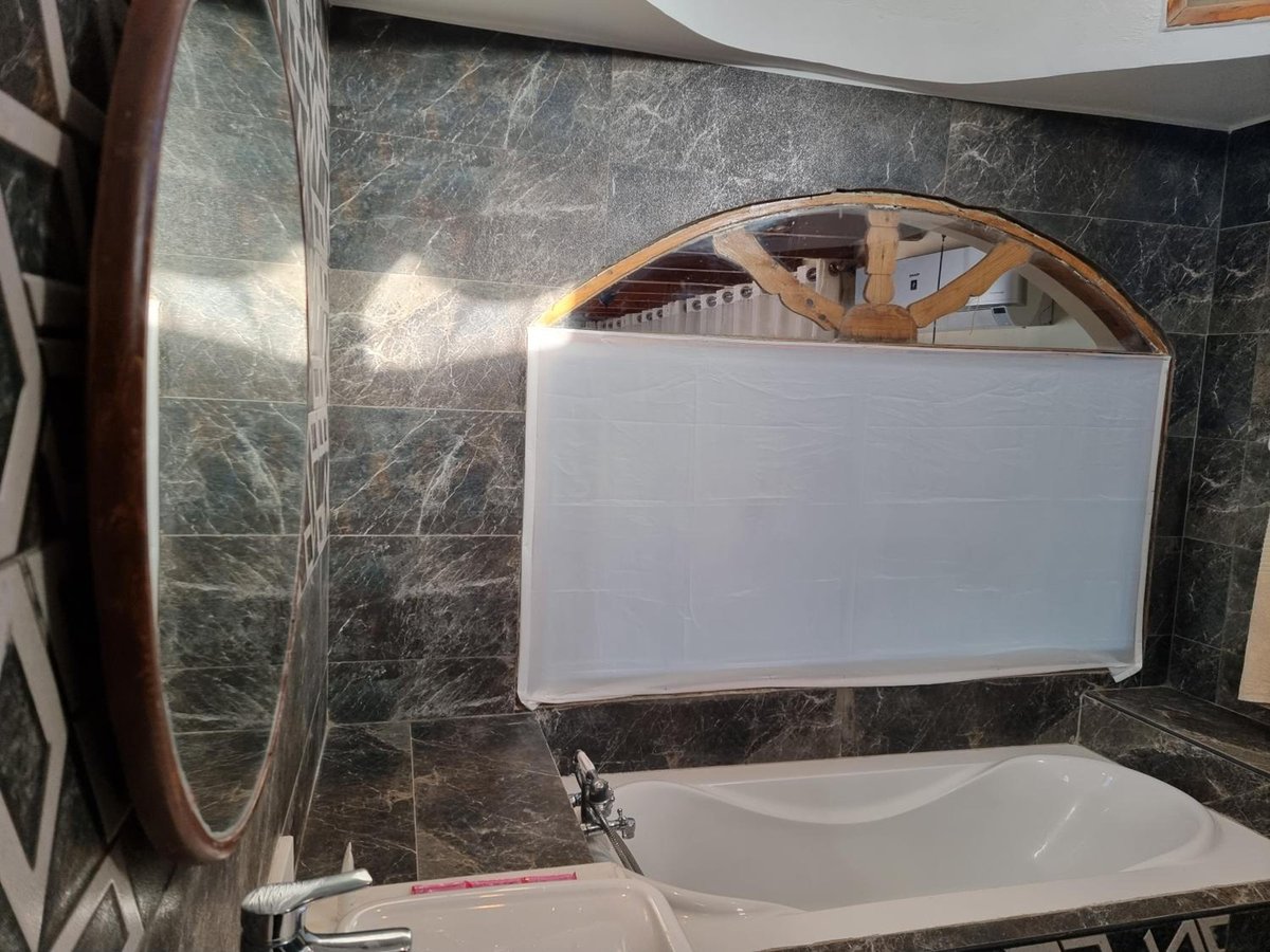 The Bedouin Moon Hotel Dahab bathroom with a bathtub and dark tiled walls.