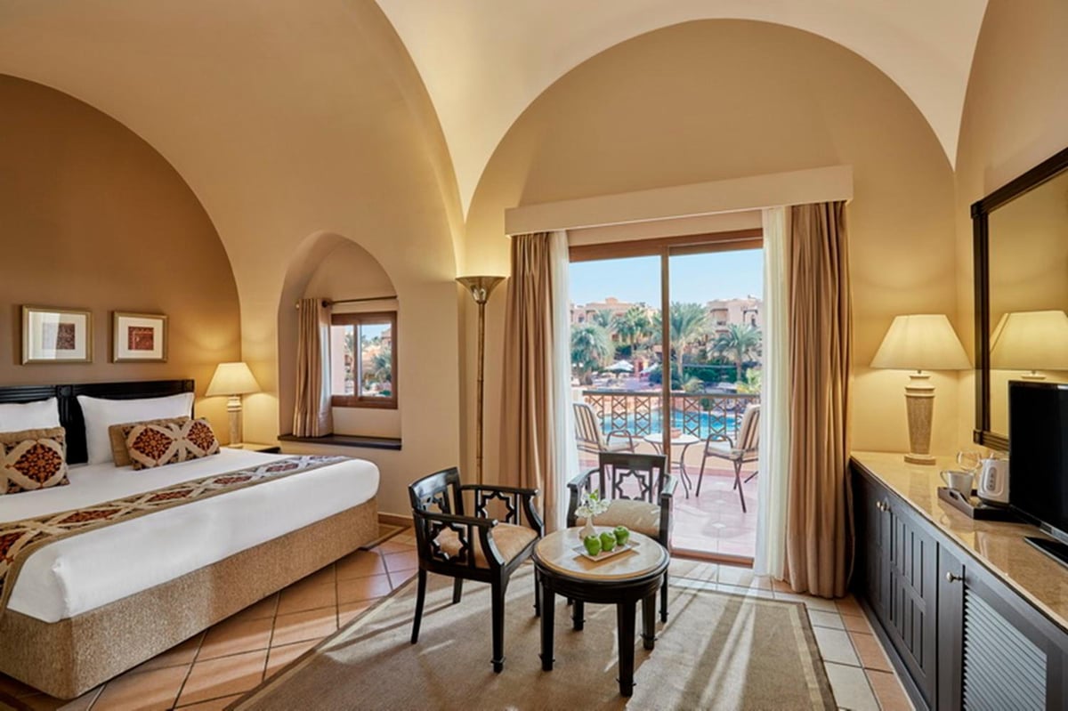 Steigenberger Coraya Beach (Adults Friendly 16+) guest room with an arched ceiling and glass balcony doors.