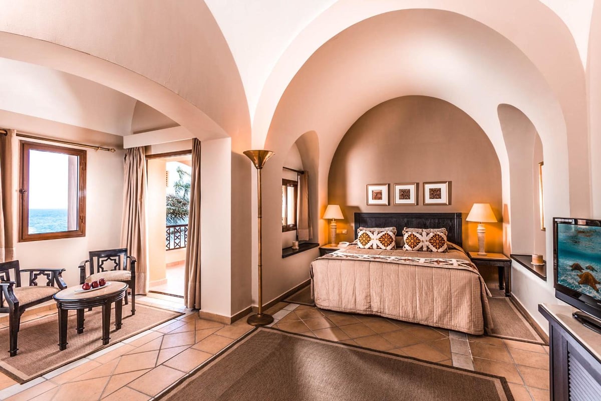 Steigenberger Coraya Beach (Adults Friendly 16+) bedroom with arched ceilings and a sea-view balcony.