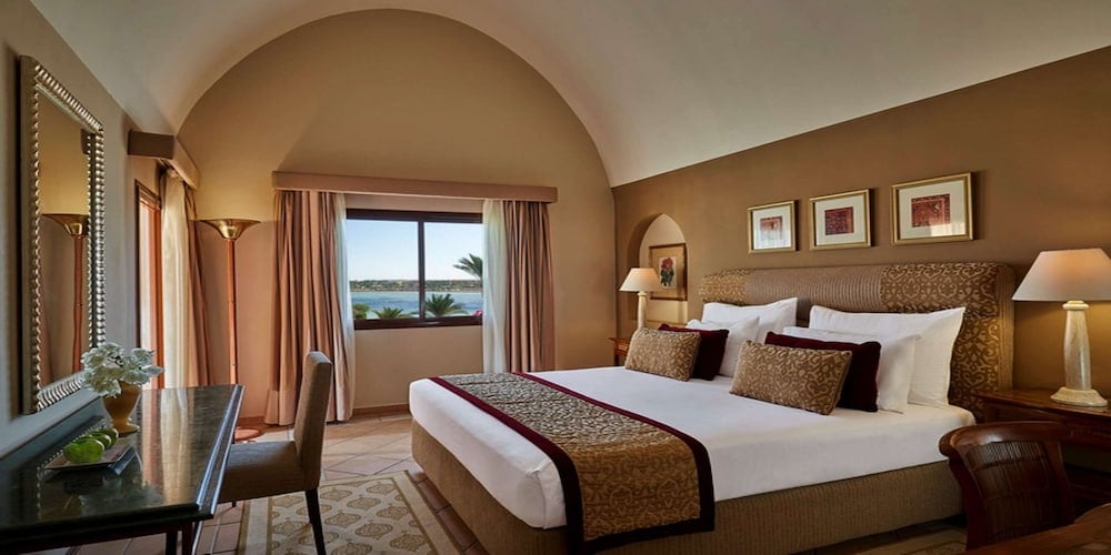 Steigenberger Coraya Beach bedroom with a large bed and arched ceiling.