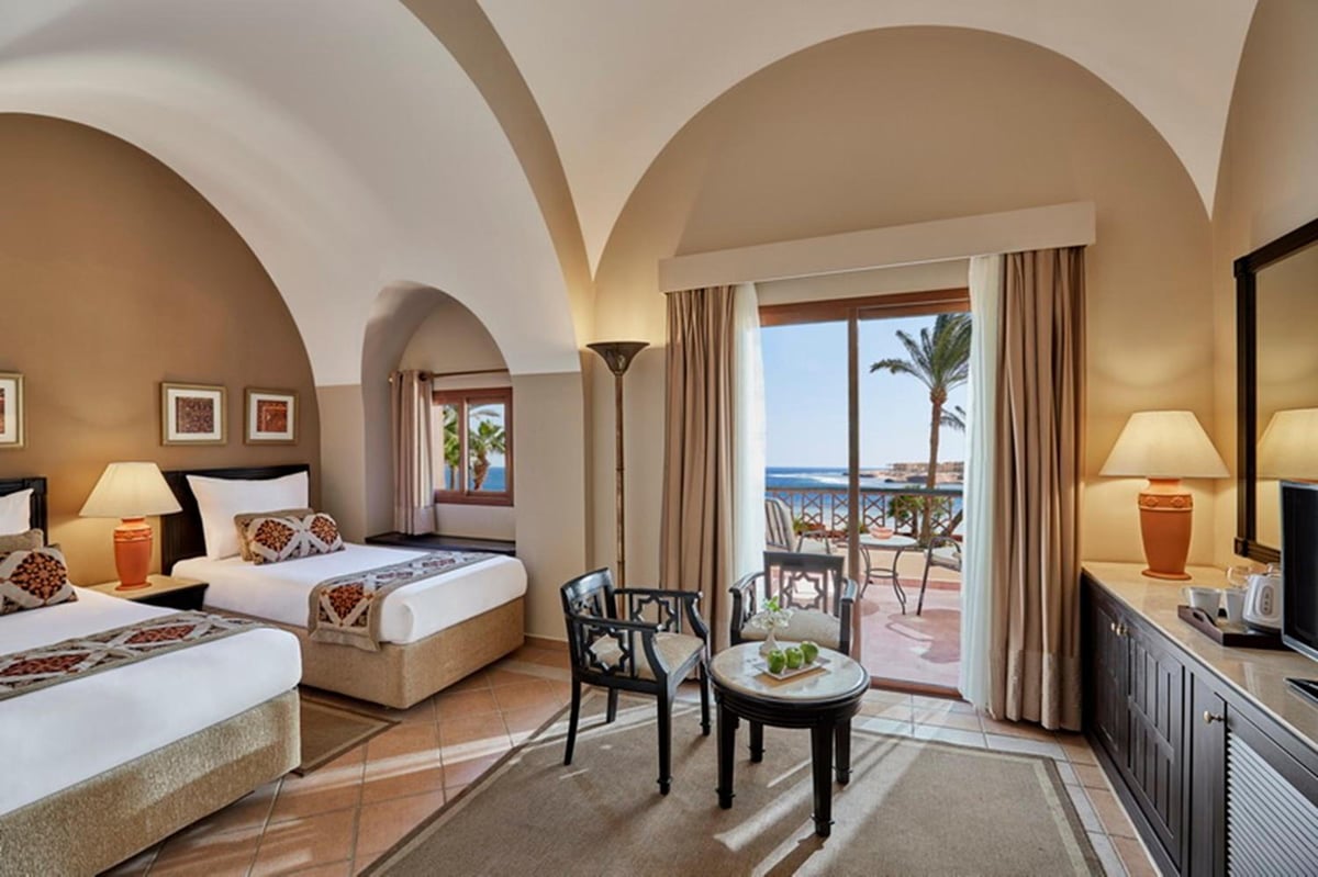 Steigenberger Coraya Beach (Adults Friendly 16+) twin bedroom with arched ceilings and balcony doors.