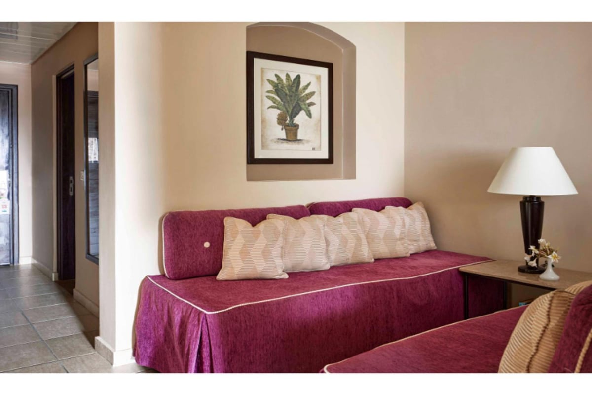 JAZ Lamaya Resort sitting area with magenta daybeds and framed botanical art.