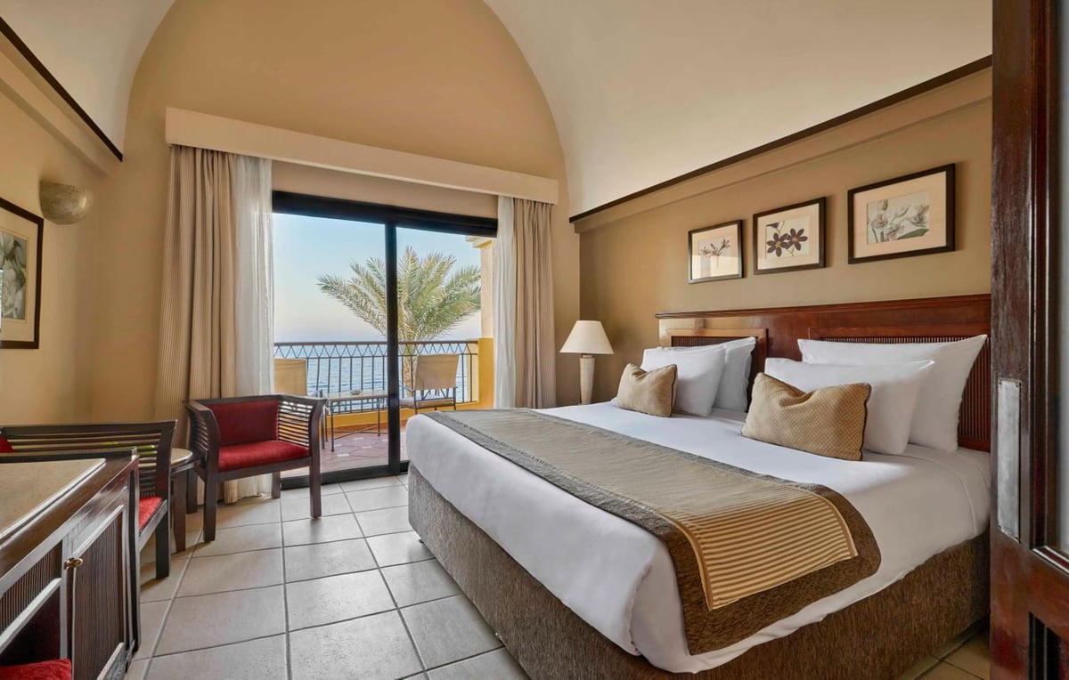 JAZ Lamaya Resort bedroom with a large bed and sliding doors to a balcony.