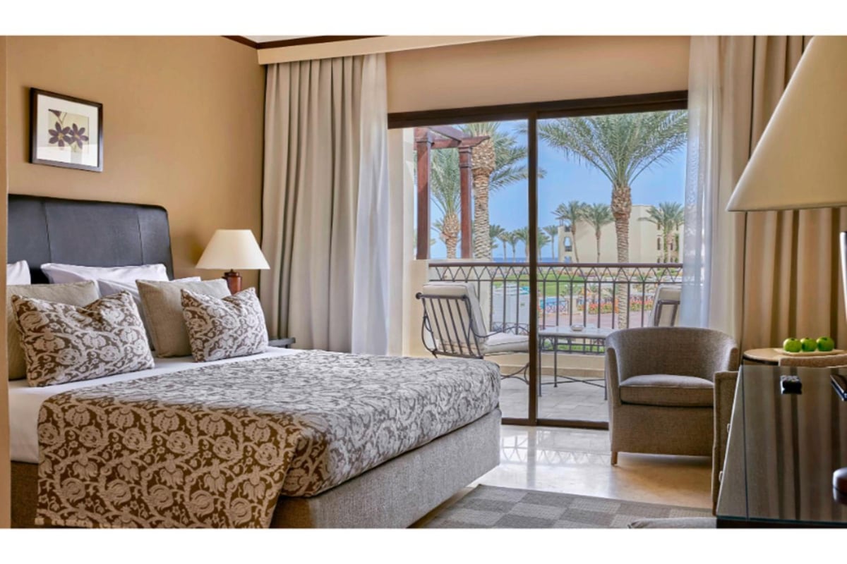 JAZ Lamaya Resort bedroom with a patterned bed and a balcony.