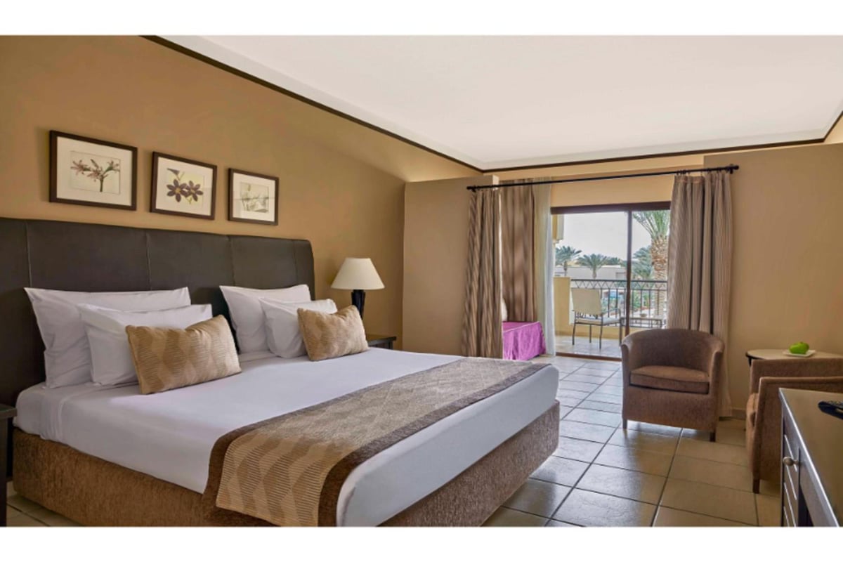 JAZ Lamaya Resort guest room with a large bed and a balcony.