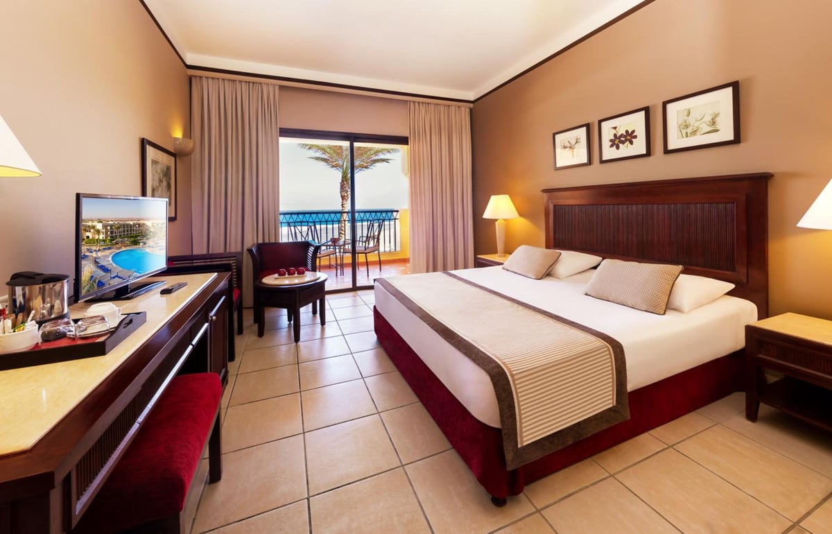 JAZ Lamaya Resort guest room with a large bed and balcony.
