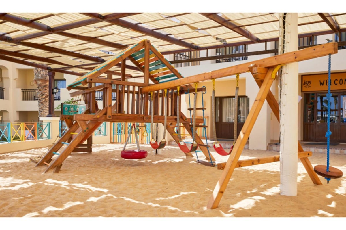 JAZ Lamaya Resort playground with a wooden climbing frame and swings.