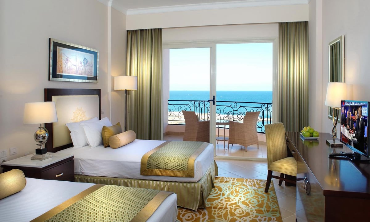 Tolip Hotel Alexandria guest room with twin beds and a sea-view balcony.