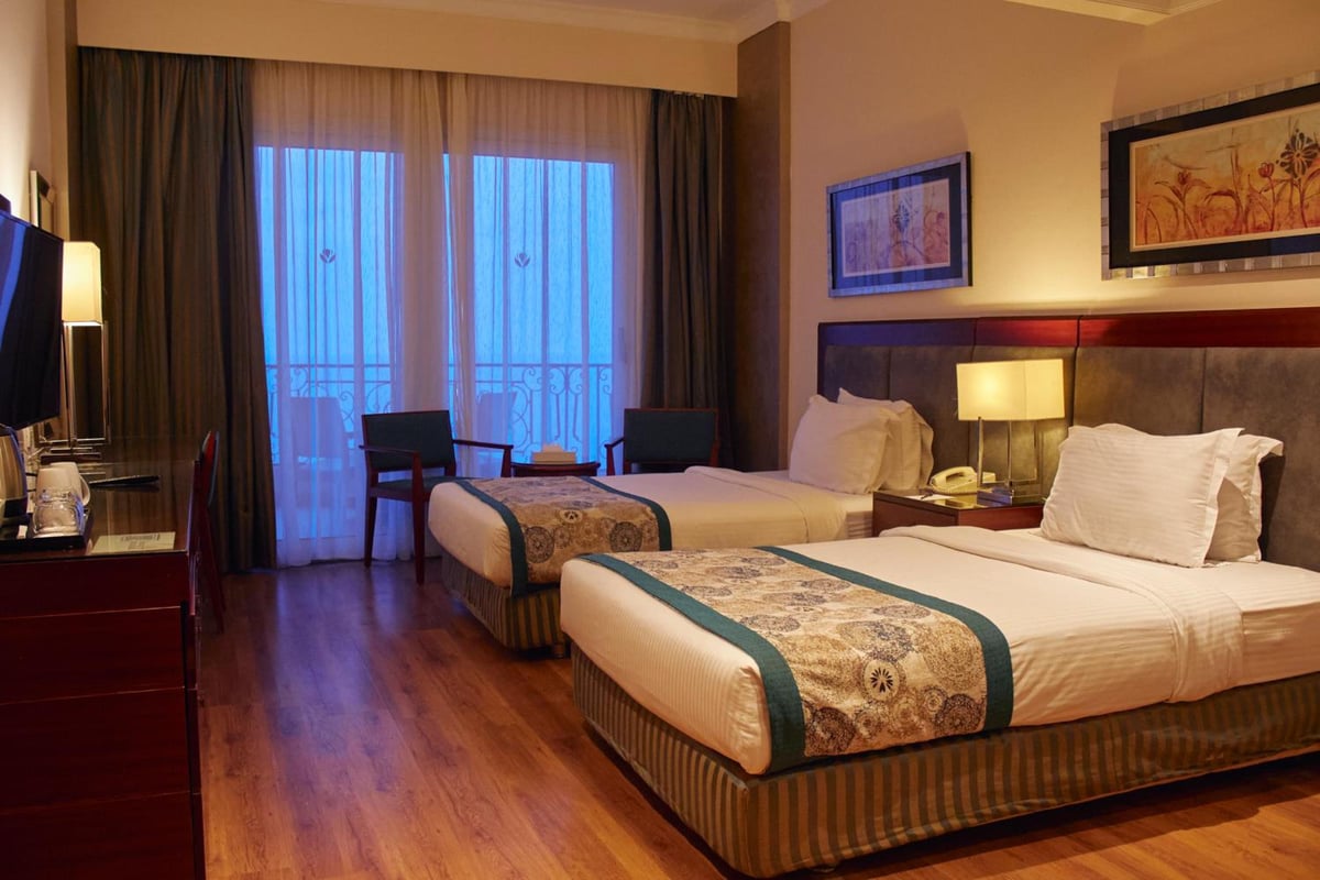 Tolip Hotel Alexandria twin room with two beds and glass doors to a balcony.
