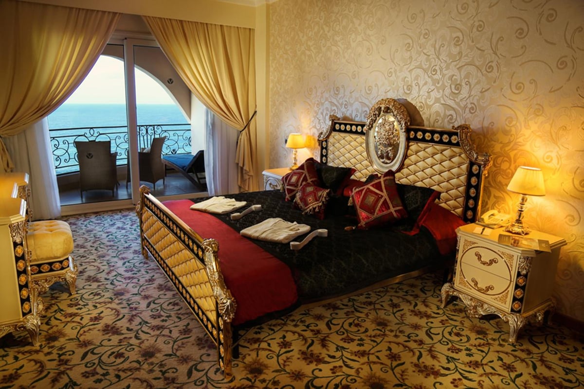 Tolip Hotel Alexandria bedroom with an ornate bed and balcony doors overlooking the water.