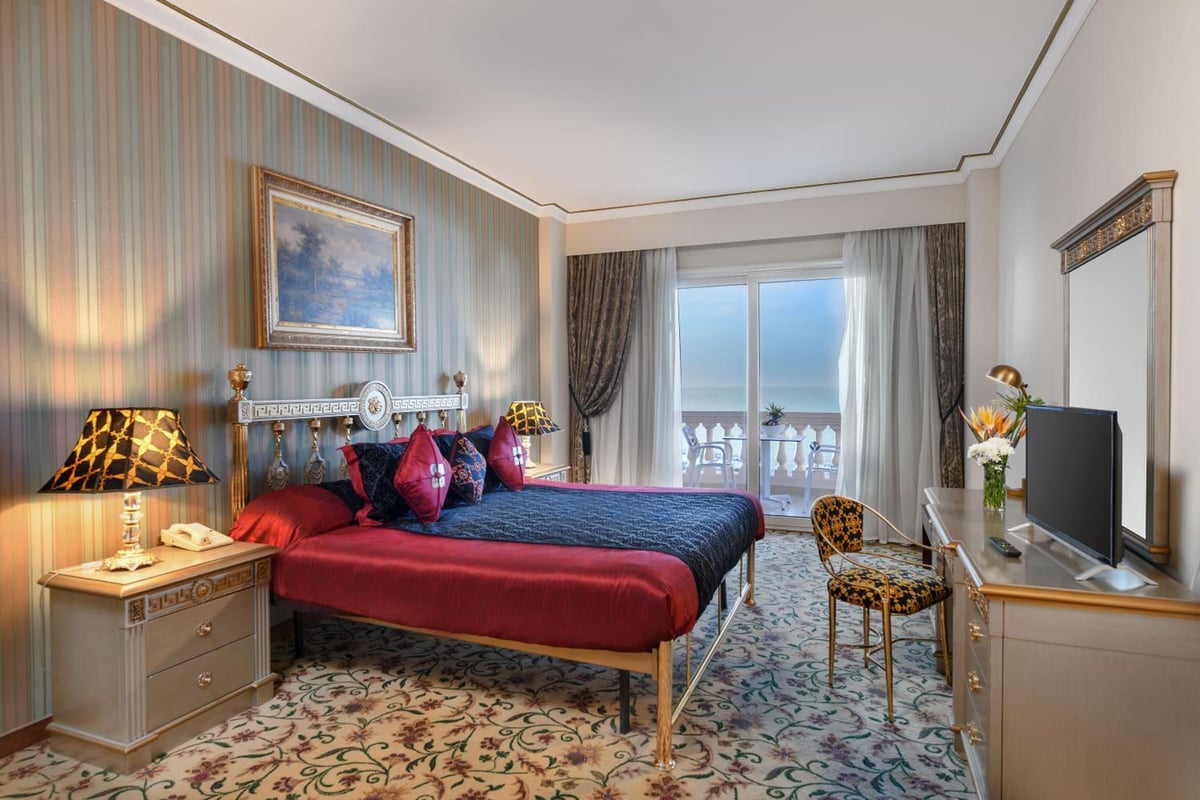 Tolip Hotel Alexandria guest bedroom with a large bed and glass balcony doors.
