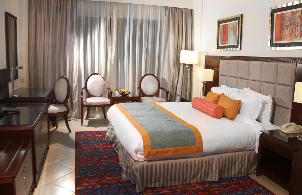 Tolip Hotel Alexandria guest bedroom with a padded headboard and full-length curtains.