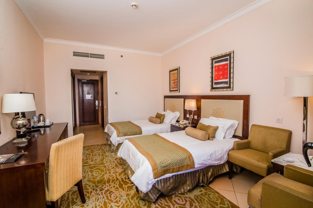 Tolip Hotel Alexandria guest room with two beds and an armchair.