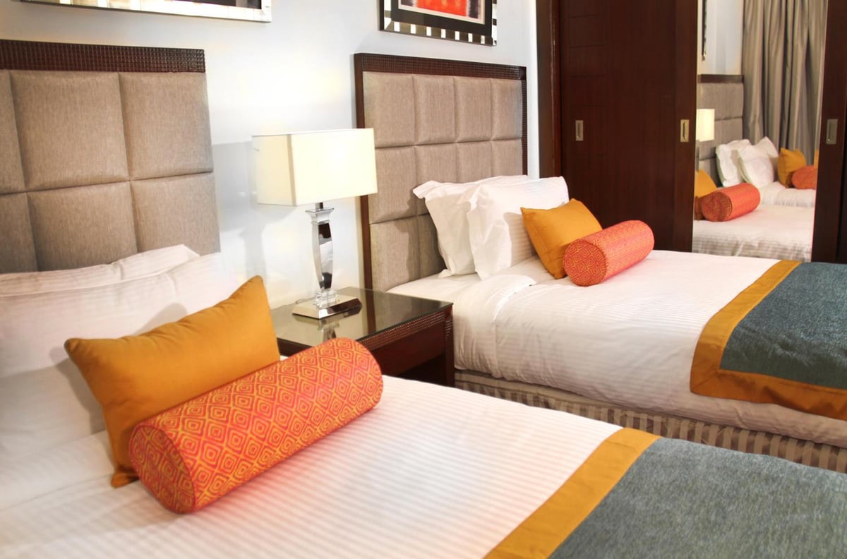 Tolip Hotel Alexandria twin bedroom with upholstered headboards and orange accents.
