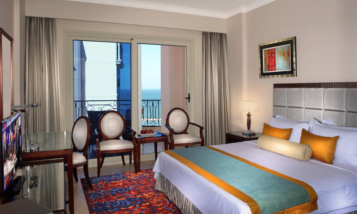 Tolip Hotel Alexandria guest room with a large bed and balcony doors.