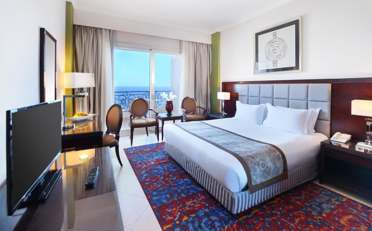 Tolip Hotel Alexandria bedroom with a large bed and a window overlooking the water.