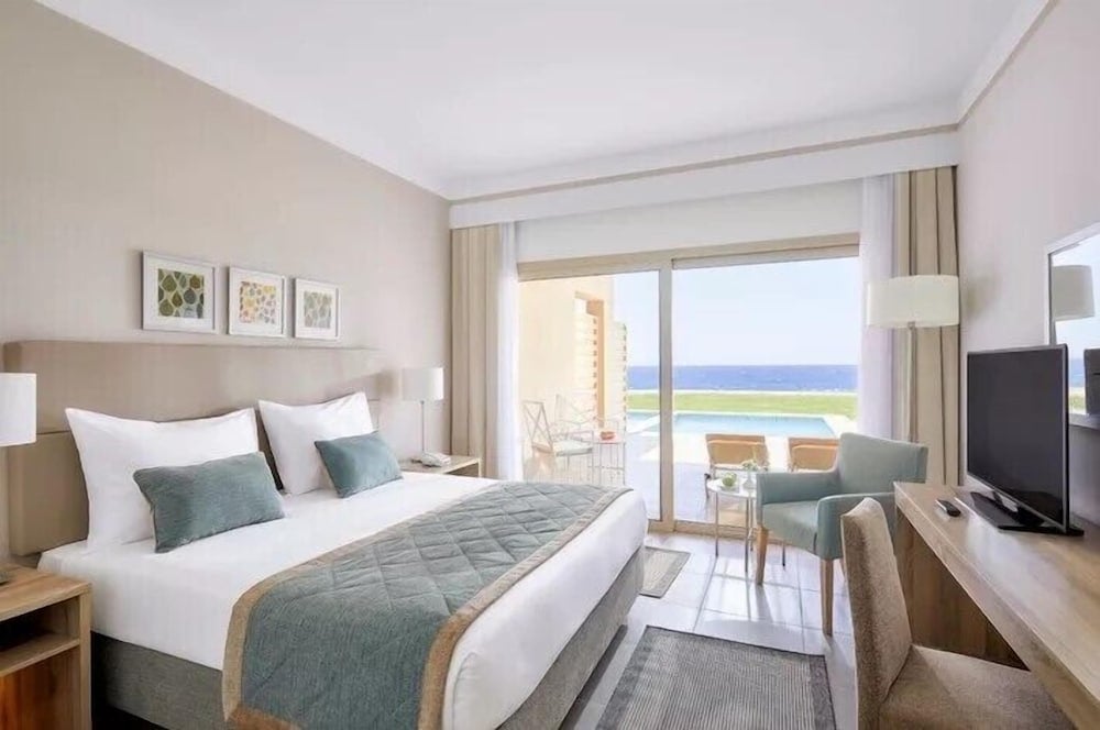 JAZ Elite Maraya guest room with a bed and a balcony overlooking the sea.