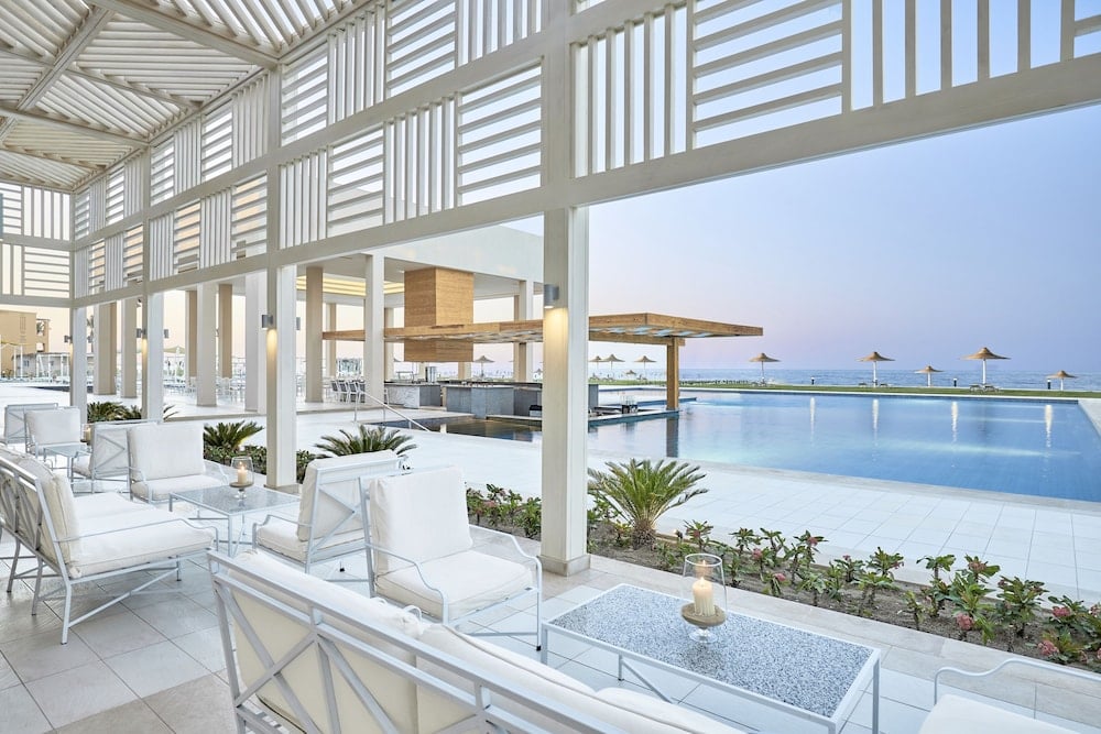 JAZ Elite Maraya covered terrace with white seating and a pool beside the sea.