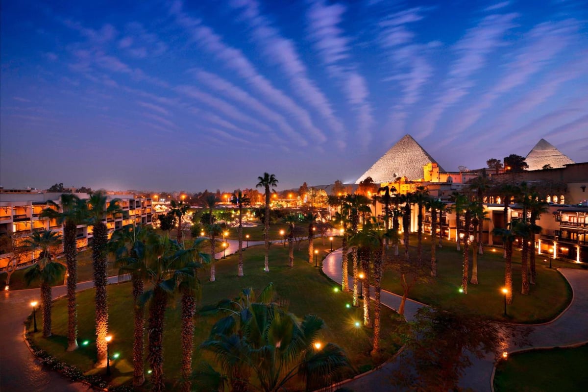 Marriott Mena House Cairo garden courtyard with palm-lined pathways and pyramids in the background.
