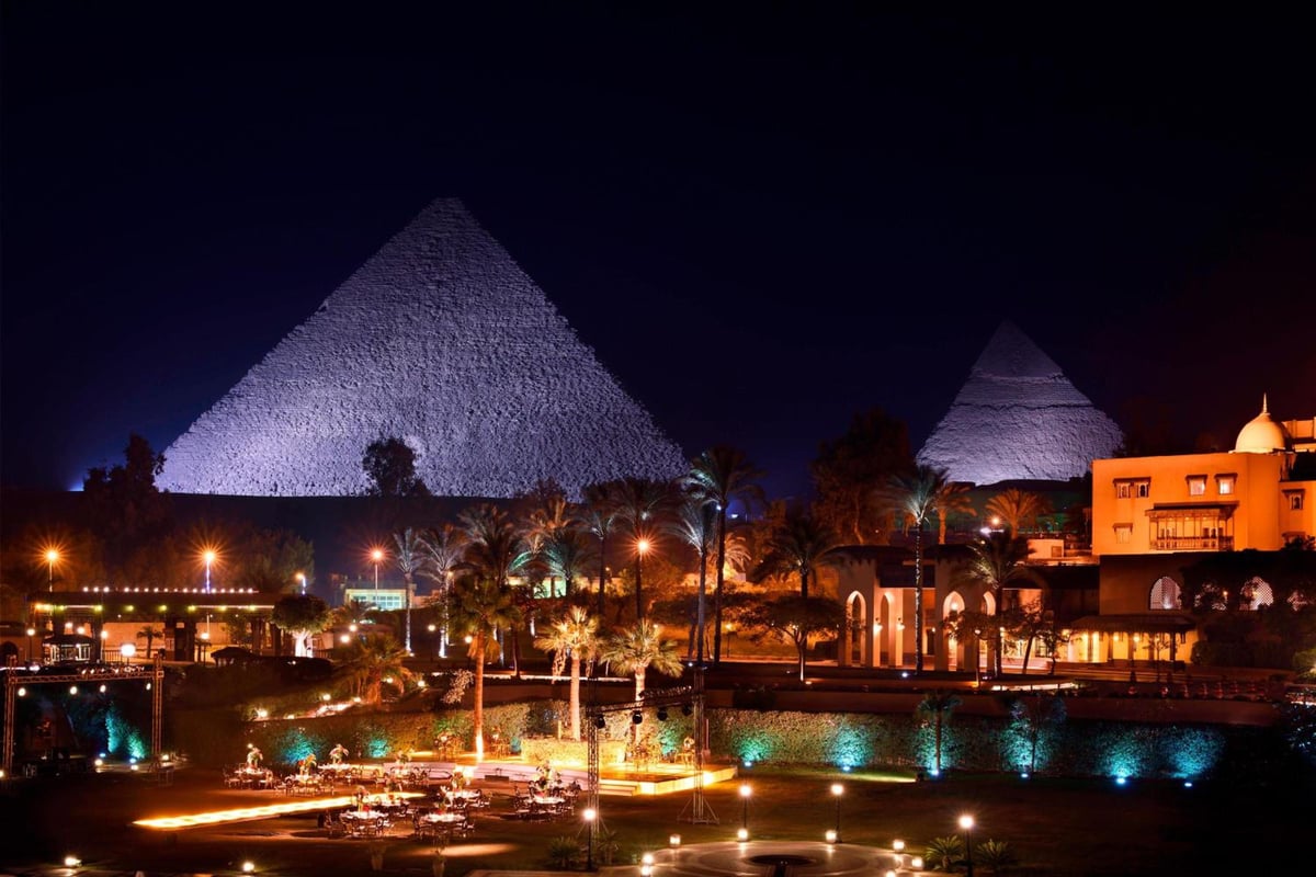 Marriott Mena House Cairo grounds with illuminated pyramids and palm-lined gardens.
