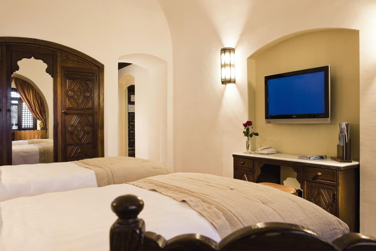 Movenpick Resort Sharm El Sheikh twin bedroom with two beds and carved wooden doors.