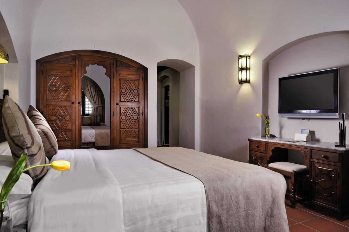 Movenpick Resort Sharm El Sheikh bedroom with a carved wooden wardrobe and wall-mounted TV.