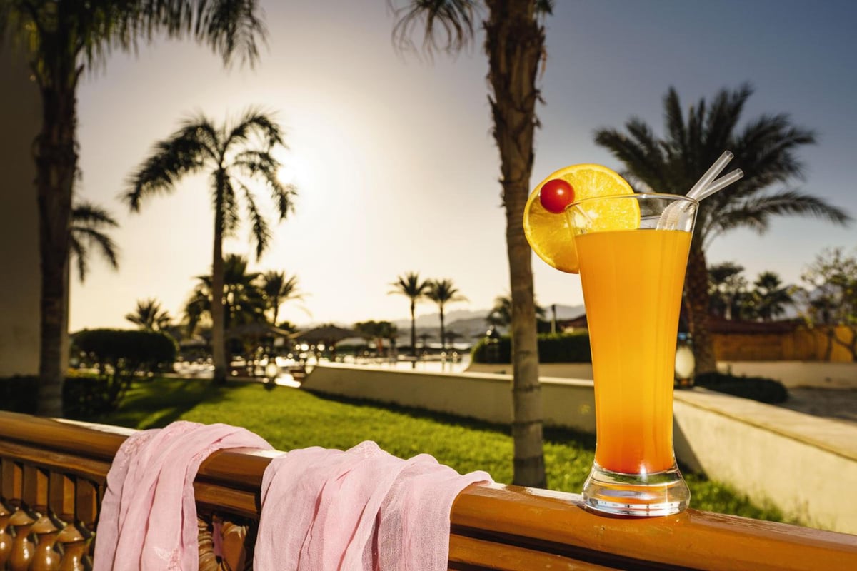 Movenpick Resort Sharm El Sheikh terrace with an orange drink and palm trees.