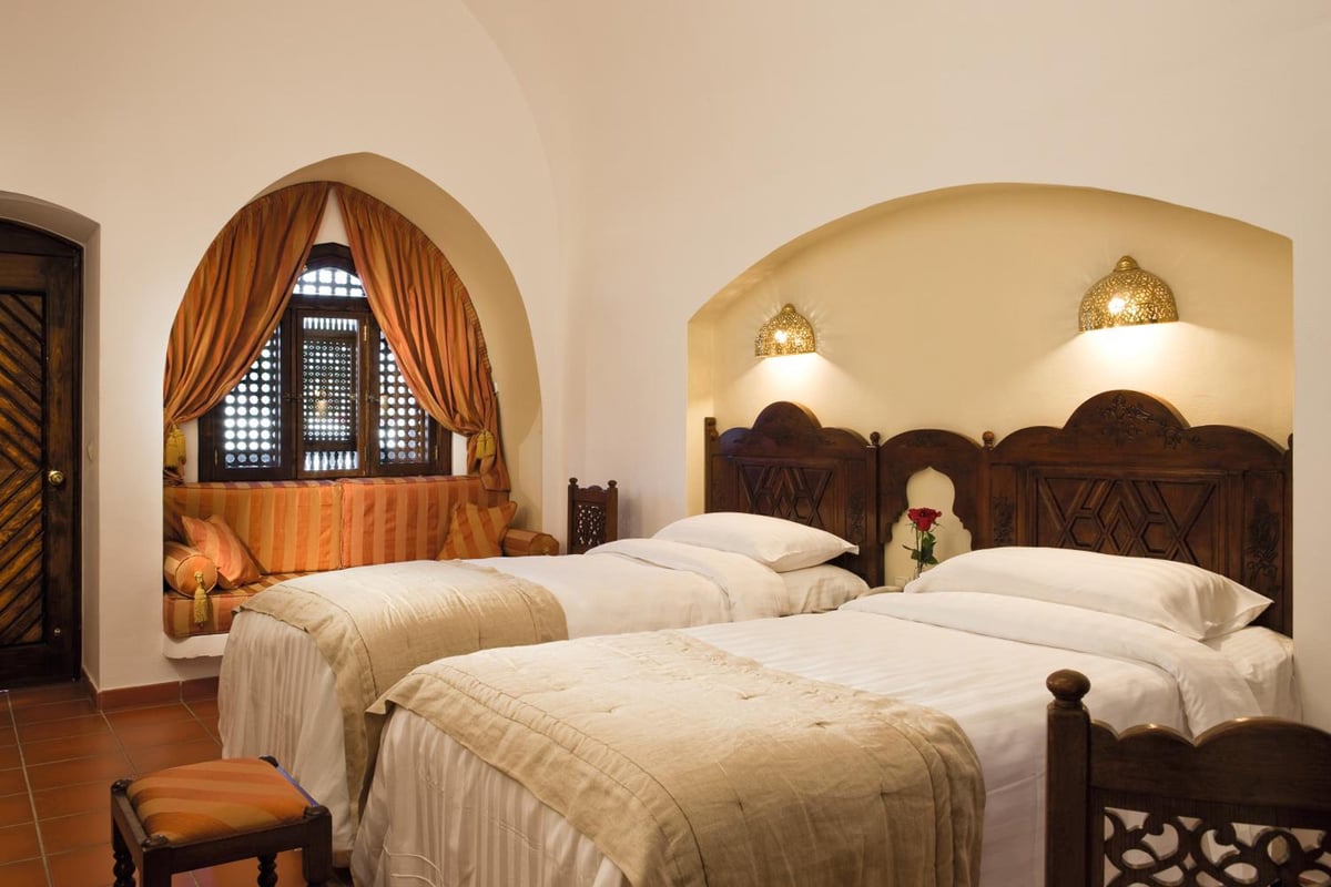Movenpick Resort Sharm El Sheikh twin bedroom with two beds and carved wooden headboards.