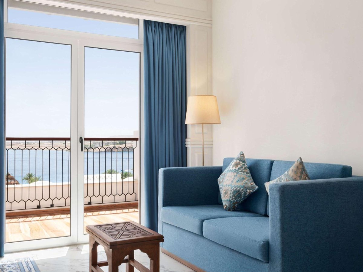 Movenpick Resort Sharm El Sheikh sitting area with a blue sofa and balcony doors.