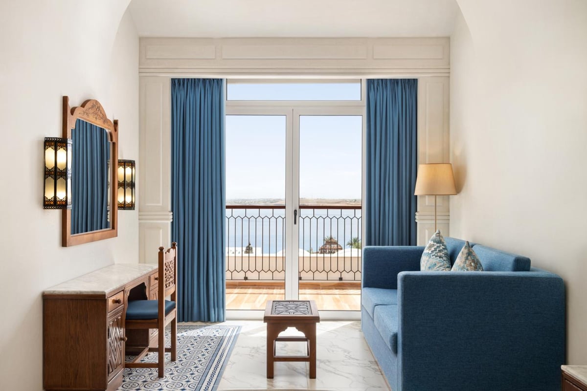 Movenpick Resort Sharm El Sheikh sitting area with a blue sofa and balcony doors.