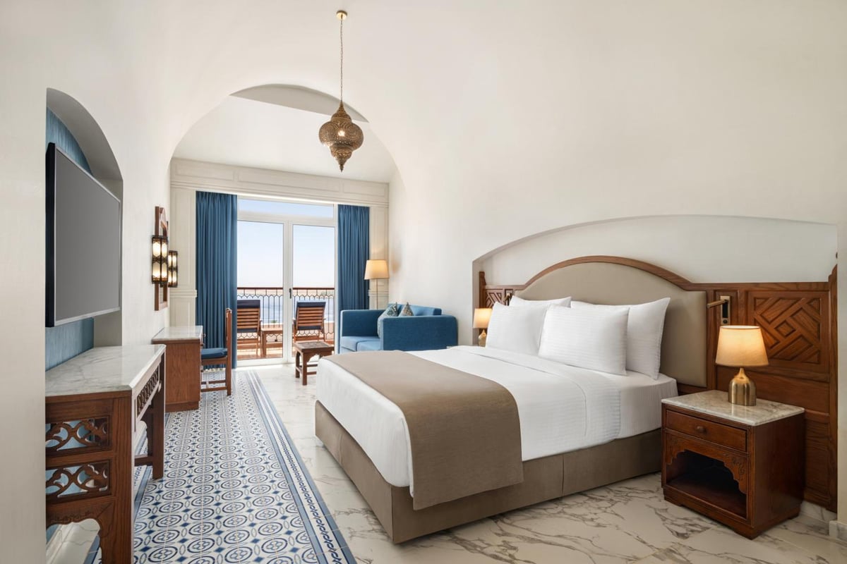 Movenpick Resort Sharm El Sheikh bedroom with a large bed and blue curtains.