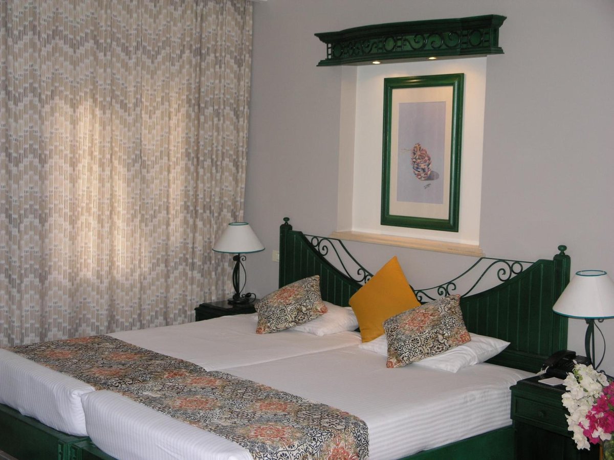 Swiss Inn Resort Dahab bedroom with a green headboard and patterned curtains.