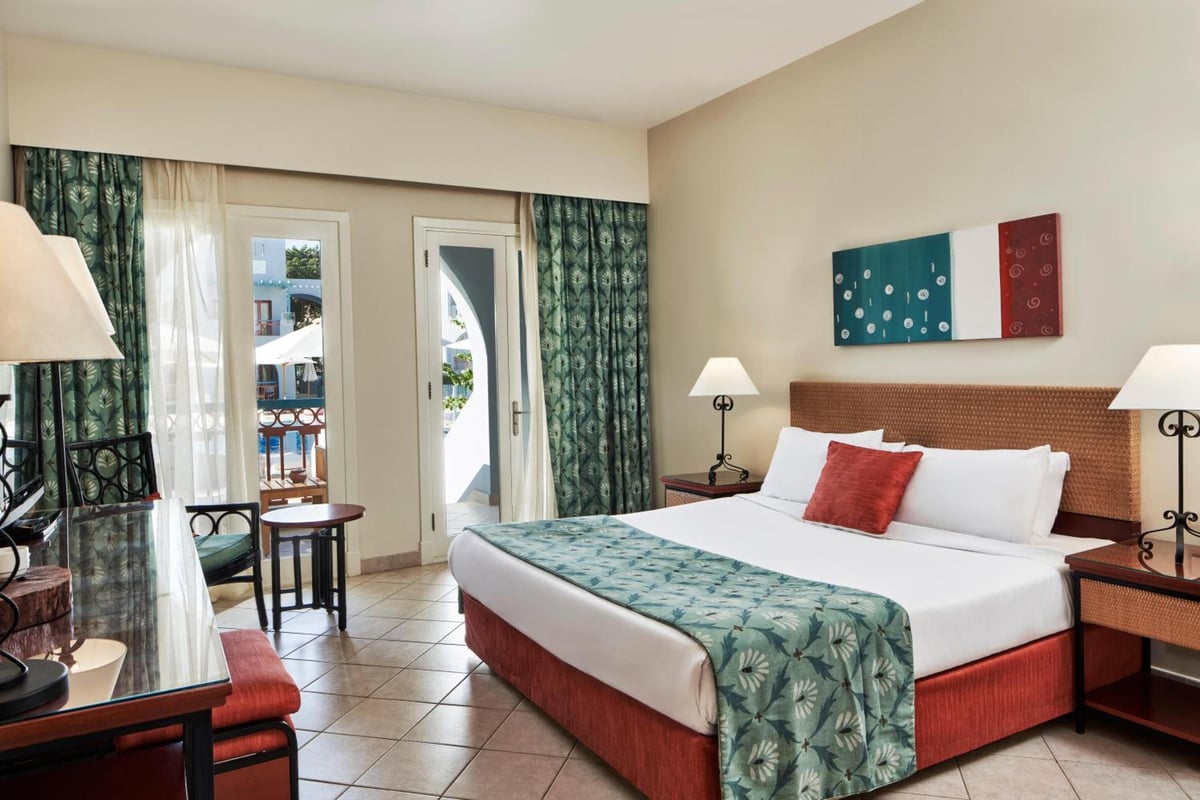 Fanadir Hotel El Gouna bedroom with a bed and balcony doors.