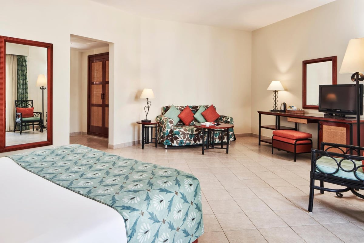 Fanadir Hotel El Gouna guest room with a patterned bed and a sofa.