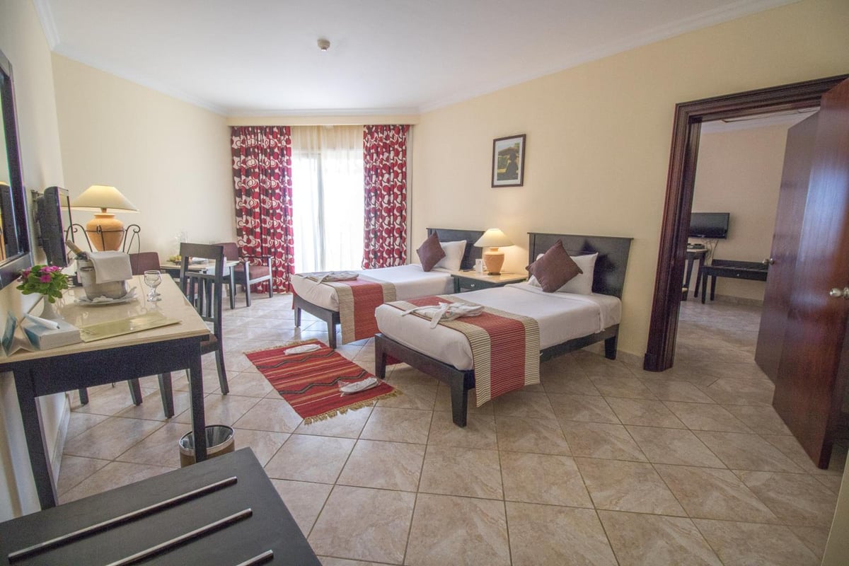 Casa Mare Resort Marsa Alam guest room with twin beds and red patterned curtains.