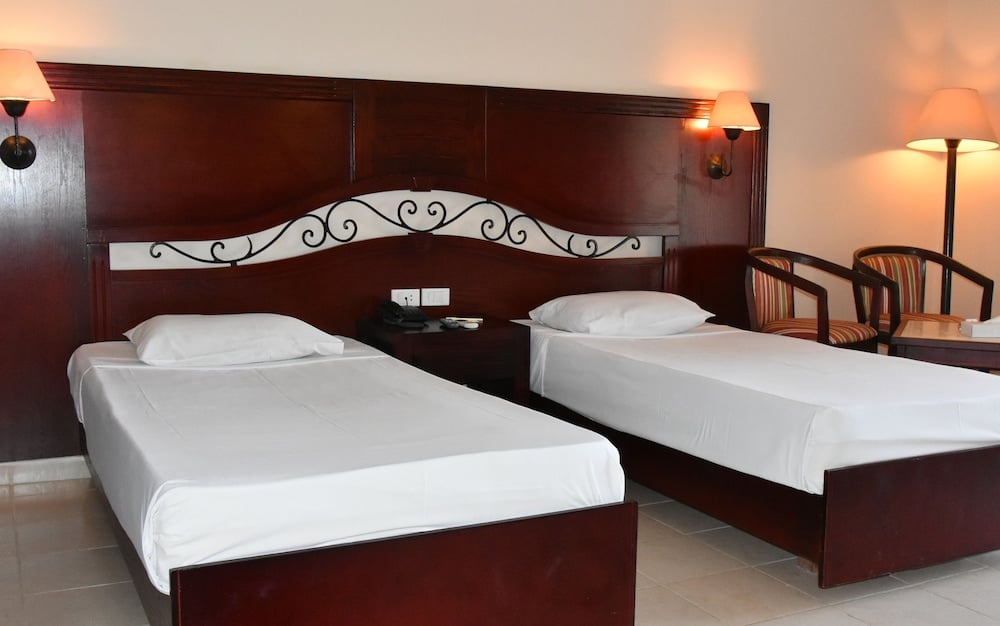Brayka Bay Resort twin bedroom with two single beds and a dark wood headboard.