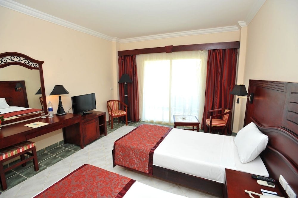 Brayka Bay Resort guest bedroom with a large bed and red curtains.