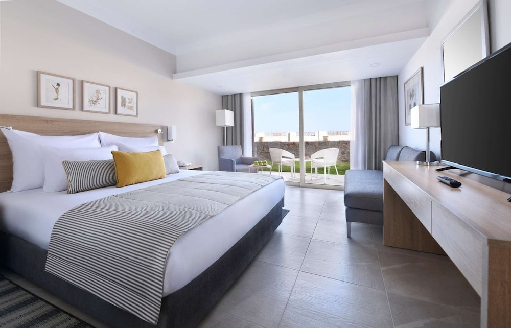 JAZ Costa Mares guest room with a large bed and balcony seating.