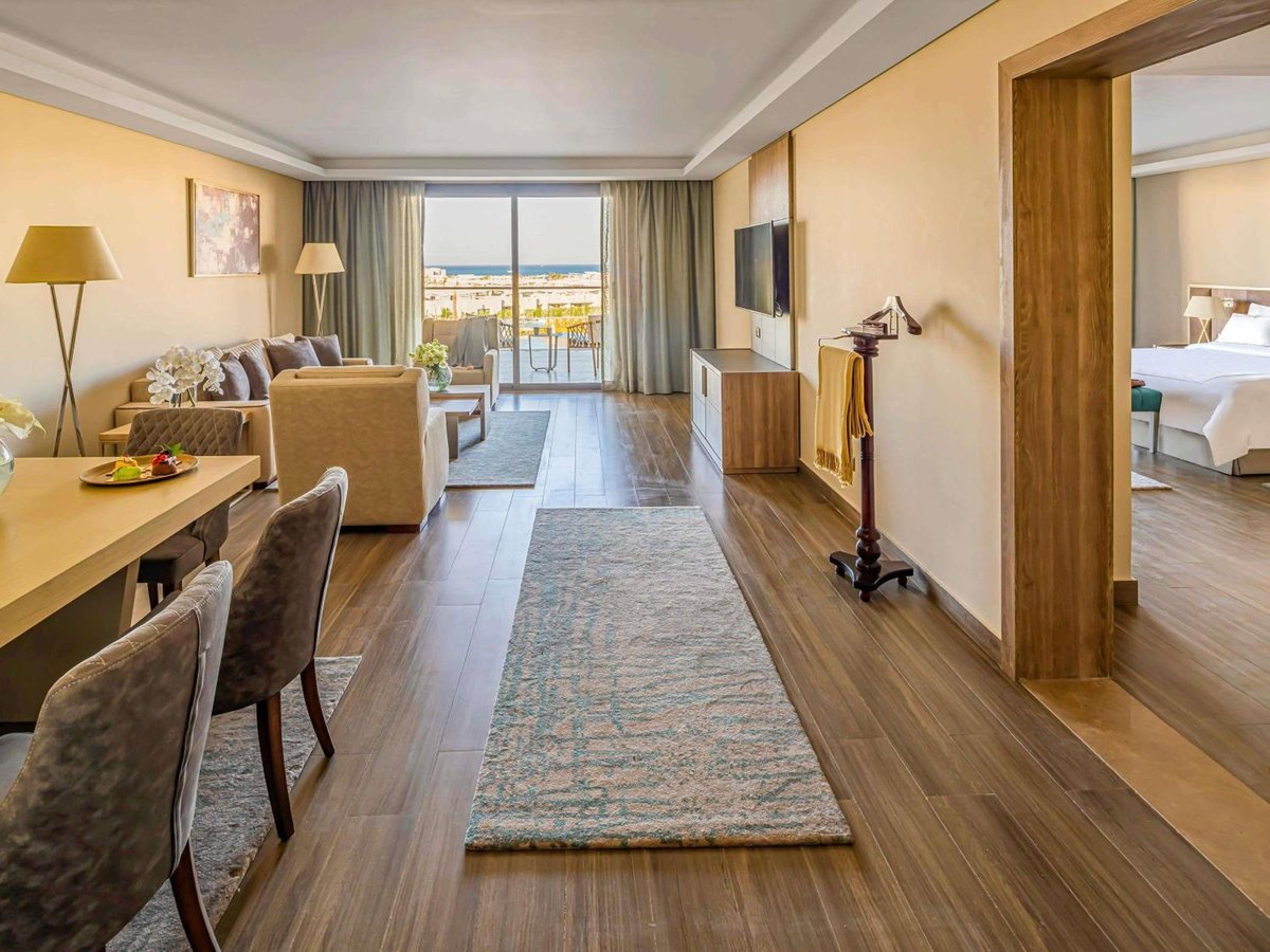 Rixos Premium Magawish Suites & Villas living room with dining area and balcony.