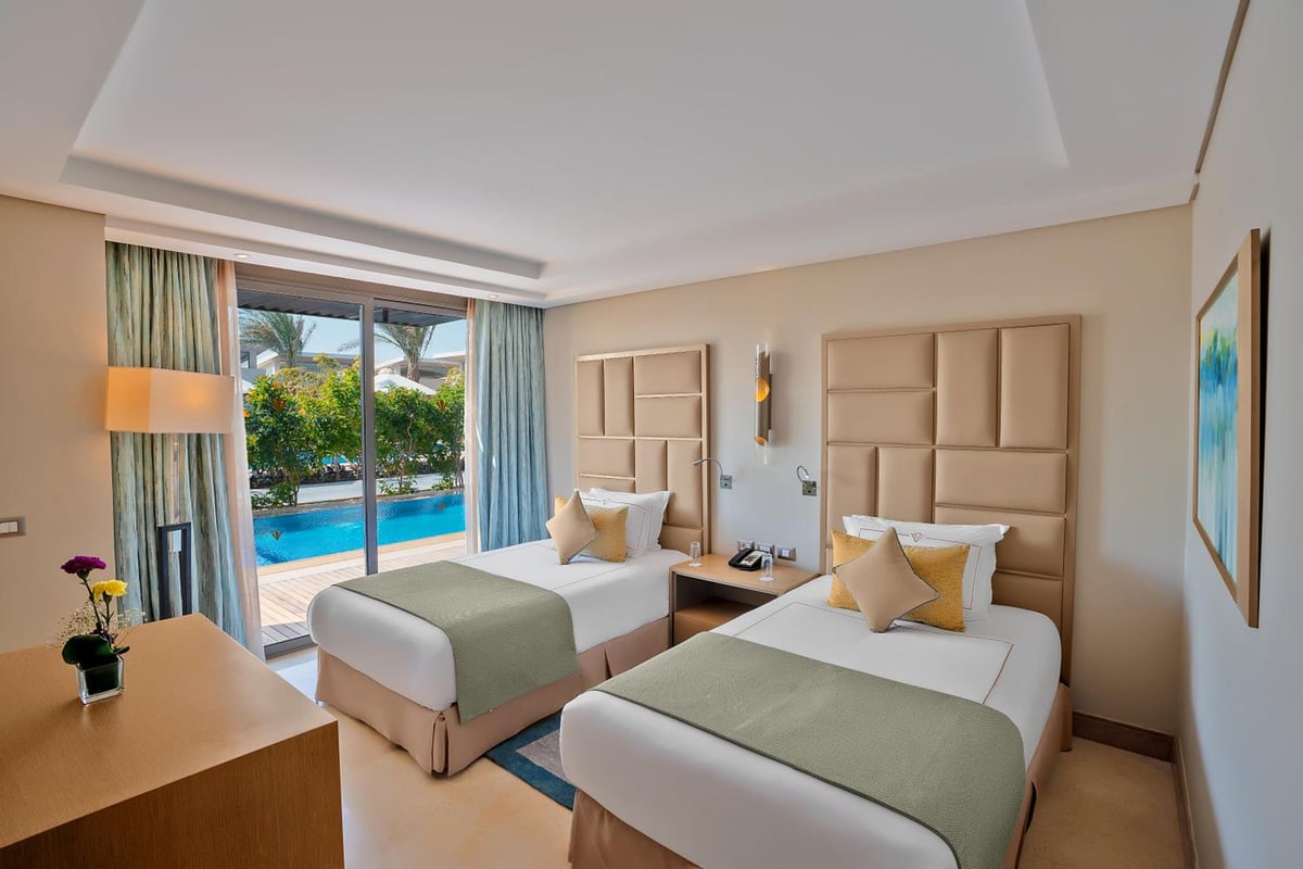 Rixos Premium Magawish Suites & Villas twin bedroom with two beds and a pool view.