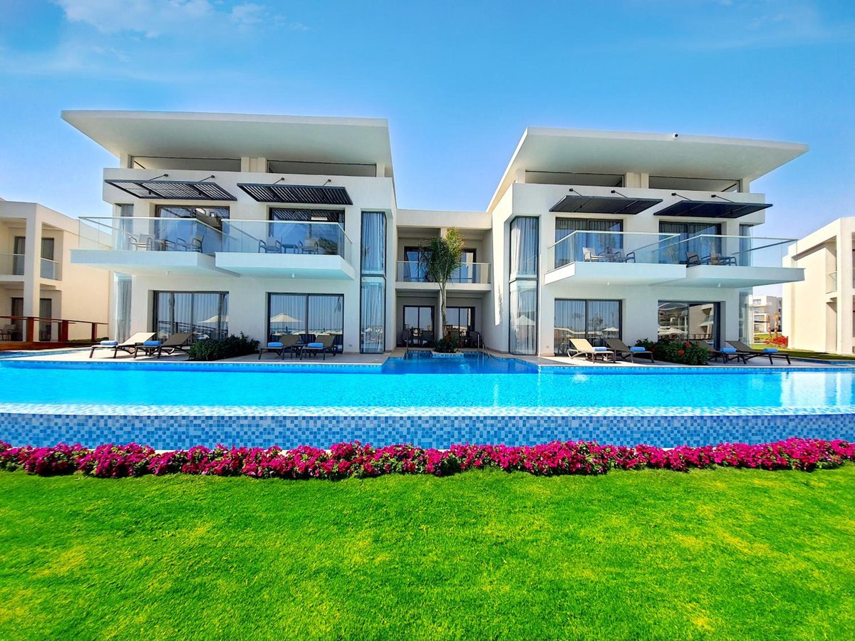 Rixos Premium Magawish Suites & Villas resort pool with modern villas and a flower border.